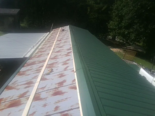 Old rusted panels beside newly installed green metal roofing — Wind Damage Roof Repair by Roofing Brothers in Hitterdal