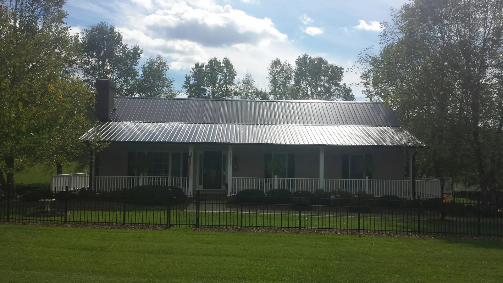 Gray metal roof on a brick ranch with a full width front porch — Gutter Guard Installation work by our crew in Hitterdal