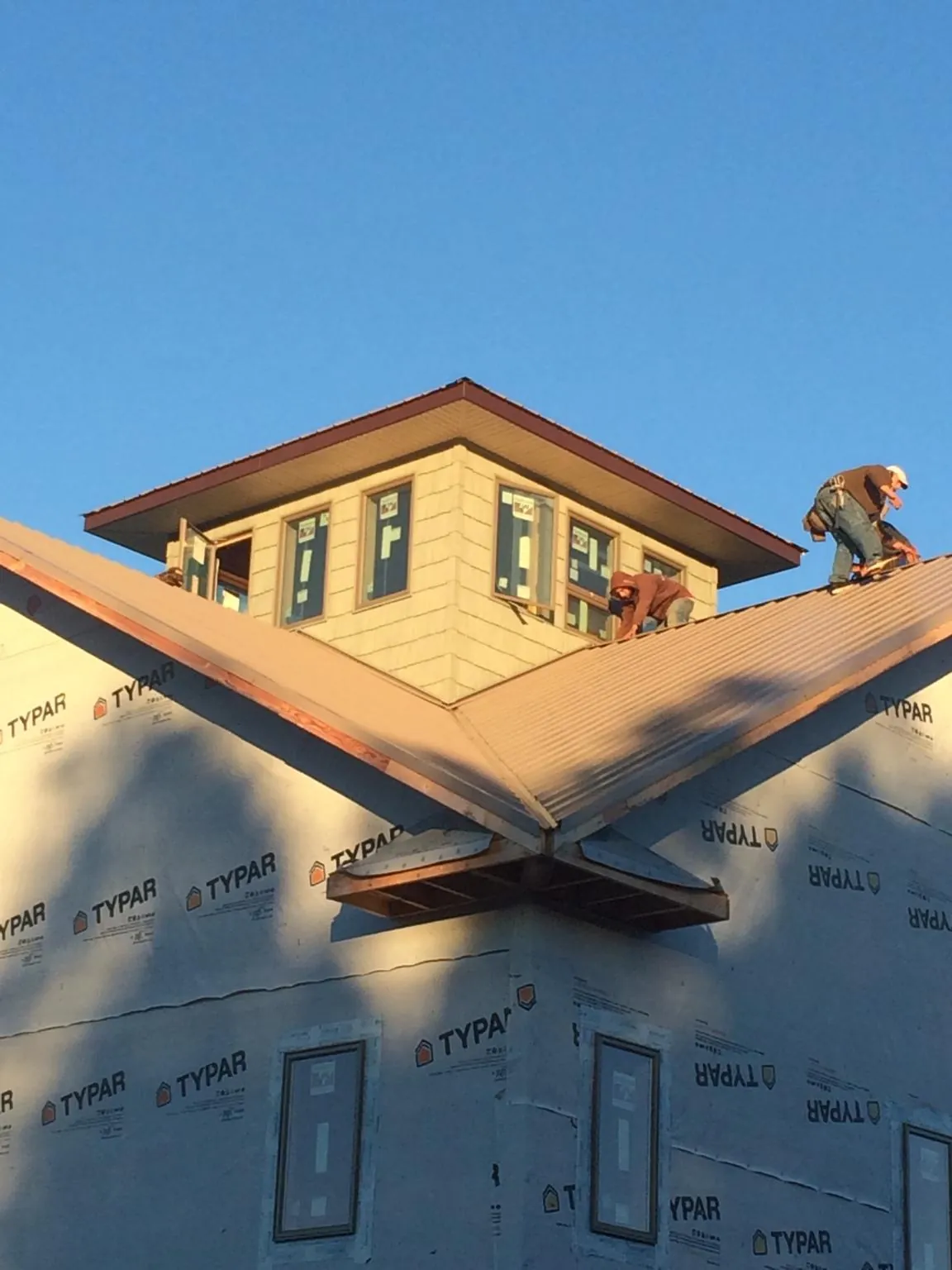 Roofers working around a rooftop cupola on a new metal roof at sunset — Roof Waterproofing in Hitterdal by Roofing Brothers